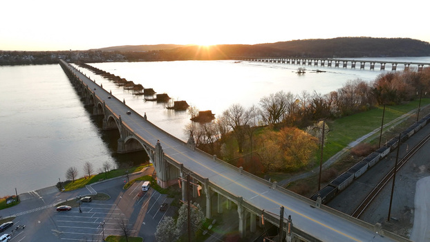 Aerial view of the Veterans Memorial Bridge spanning the Susquehanna River at sunset with golden light reflecting on the water in Columbia Pennsylvania United States.