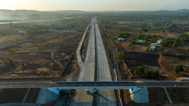 Aerial view of JNPT Highway Badlapur Tunnel featuring a multi lane road stretching through a rural landscape with dry fields and sparse vegetation in Badlapur Maharashtra India. Aerial view of JNPT Highway Badlapur Tunnel featuring a multi lane road stretching through a rural landscape with dry fields and sparse vegetation in Badlapur Maharashtra India.