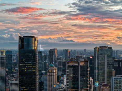 Aerial view of the Jalan Jendral Sudirman skyline with modern skyscrapers and glass towers under a dramatic sunset sky in Kecamatan Setiabudi Daerah Khusus Ibukota Indonesia. Aerial view of the Jalan Jendral Sudirman skyline with modern skyscrapers and glass towers under a dramatic sunset sky in Kecamatan Setiabudi Daerah Khusus Ibukota Indonesia.