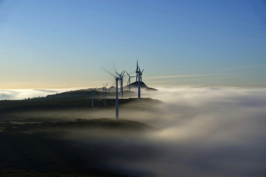 Aerial view of wind turbines standing on the ridge of Bica da Cana peak above a thick layer of clouds at sunset in Unhais da Serra Madeira Portugal.