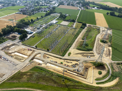 Aerial view of the Neufinsing electrical substation with power lines construction equipment and surrounding agricultural fields in Finsing Bayern Germany.
