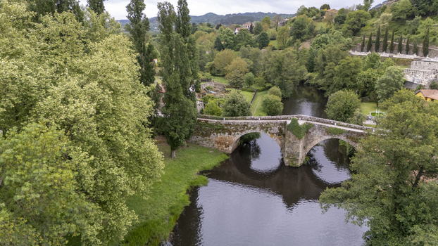 Aerial view of Ponte de Vilanova stone bridge crossing the Arnoia River surrounded by lush green trees and vegetation Allariz Ourense Spain. Aerial view of Ponte de Vilanova stone bridge crossing the Arnoia River surrounded by lush green trees and vegetation Allariz Ourense Spain.
