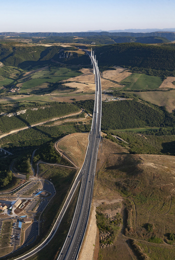 Aerial view of the Millau Viaduct soaring through the Tarn River valley a modern marvel of engineering amidst the golden fields and green hills Millau France. Aerial view of the Millau Viaduct soaring through the Tarn River valley a modern marvel of engineering amidst the golden fields and green hills Millau France.
