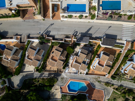 Aerial view of residential houses with terracotta roofs and swimming pools in Moraira Valencian Community Spain.