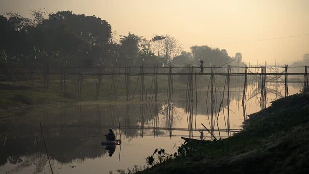 View of a bamboo bridge over a river at sunrise Bangladesh.