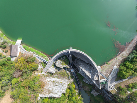Aerial view of Barrage de Montsalvens arch dam with its curved concrete wall holding back green water surrounded by trees. Chatel sur Montsalvens Fribourg Switzerland. Aerial view of Barrage de Montsalvens arch dam with its curved concrete wall holding back green water surrounded by trees. Chatel sur Montsalvens Fribourg Switzerland.