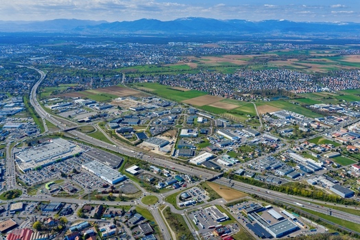 Aerial view of a sprawling cityscape where industrial estates meet residential areas divided by highways all under a gentle sky Sausheim Grand Est France.