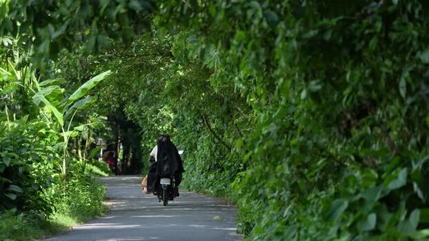 View of a person riding a motorcycle on a rural road Bangladesh.