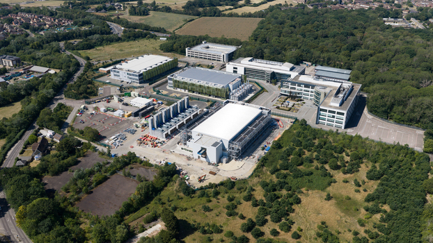 Aerial view of the Kao Data campus featuring modern data center buildings surrounded by lush woodland and access roads in Harlow England United Kingdom. Aerial view of the Kao Data campus featuring modern data center buildings surrounded by lush woodland and access roads in Harlow England United Kingdom.
