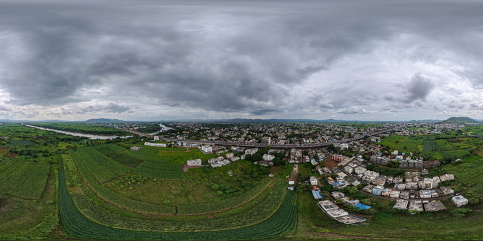 Aerial view of the town of Karad with its river bridge urban buildings and surrounding agricultural fields under a cloudy sky in Karad Maharashtra India. Aerial view of the town of Karad with its river bridge urban buildings and surrounding agricultural fields under a cloudy sky in Karad Maharashtra India.