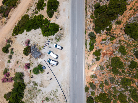 Aerial view of a straight asphalt road cutting through a rocky landscape with white vans parked on the shoulder and green scrubland Borsh Vlore County Albania. Aerial view of a straight asphalt road cutting through a rocky landscape with white vans parked on the shoulder and green scrubland Borsh Vlore County Albania.