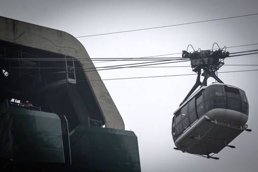 View of the Sugarloaf Mountain cable car suspended on steel wires near the concrete station under an overcast sky in Rio de Janeiro State of Rio de Janeiro Brazil.