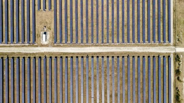 Aerial view of rows of solar panels glinting under the sun forming a geometric tapestry of light and shadow across the landscape Elkton Florida United States. Aerial view of rows of solar panels glinting under the sun forming a geometric tapestry of light and shadow across the landscape Elkton Florida United States.