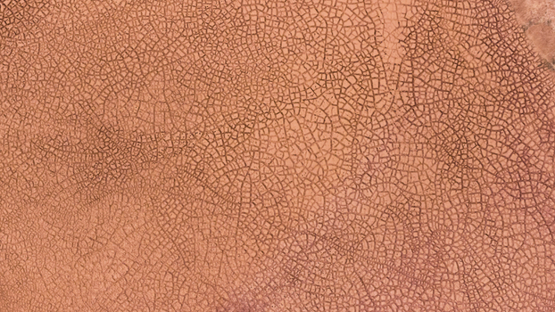 Aerial view of the intricate cracked patterns of a dried salt lake bed in the outback showcasing textured orange and brown earth formations in Kalbarri Western Australia Australia. Aerial view of the intricate cracked patterns of a dried salt lake bed in the outback showcasing textured orange and brown earth formations in Kalbarri Western Australia Australia.