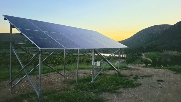 View of a solar panel array set in a rural landscape with rolling hills and a golden sunset sky in Hoeko Western Cape South Africa. View of a solar panel array set in a rural landscape with rolling hills and a golden sunset sky in Hoeko Western Cape South Africa.