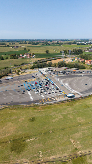 Aerial view of the Milano Sud toll plaza on the A1 motorway with vehicle traffic and highway infrastructure in Melegnano Lombardy Italy.