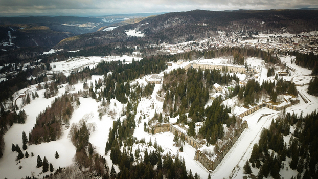Aerial view of Le Fort des Rousses surrounded by snow covered evergreen forests and historic stone fortifications in Les Rousses Bourgogne Franche Comte France.