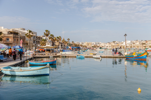 View of vibrant fishing boats bobbing on the tranquil cerulean harbor waters framed by bustling quayside and sun kissed buildings Marsaxlokk Malta. View of vibrant fishing boats bobbing on the tranquil cerulean harbor waters framed by bustling quayside and sun kissed buildings Marsaxlokk Malta.