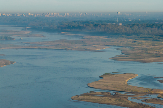 Aerial view of the Vistula River with sandbanks calm water and the distant skyline of Warsaw in the background under a clear sky in Warsaw Masovian Voivodeship Poland.
