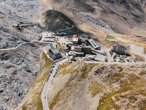 Aerial view of Stelvio Pass featuring the winding mountain road surrounding alpine peaks rocky terrain and buildings at the summit in Stilfs Trentino Alto Adige Italy.