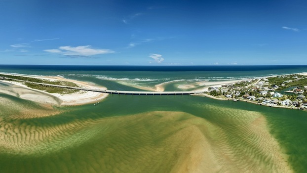 Aerial view of Matanzas Inlet showing the bridge connecting the sandy coastline turquoise waters and coastal residential areas in St. Johns County Florida United States. Aerial view of Matanzas Inlet showing the bridge connecting the sandy coastline turquoise waters and coastal residential areas in St. Johns County Florida United States.