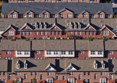 Aerial view of a dense residential complex with rows of red brick townhouses featuring gabled roofs dormer windows and symmetrical architectural details in Southfield Michigan United States.