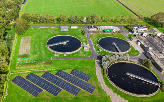 Aerial view of a wastewater treatment plant featuring circular sedimentation tanks solar panel arrays and surrounding green fields in Schagerbrug Noord Holland Netherlands. Aerial view of a wastewater treatment plant featuring circular sedimentation tanks solar panel arrays and surrounding green fields in Schagerbrug Noord Holland Netherlands.