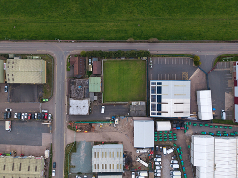 Aerial view of buildings and a green field intersected by roads contrasting with the surrounding greenery Tamworth United Kingdom. Aerial view of buildings and a green field intersected by roads contrasting with the surrounding greenery Tamworth United Kingdom.