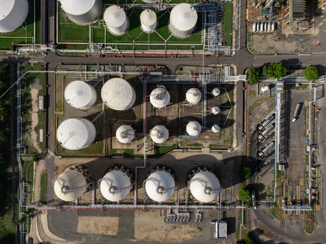 Aerial view of an industrial oil refinery featuring large white storage tanks and complex pipeline networks Bajos de Haina San Cristobal Province Dominican Republic.