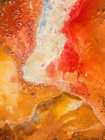 Aerial view of vibrant geothermal landscape featuring striking red orange and yellow mineral deposits across volcanic terrain in Iceland. Aerial view of vibrant geothermal landscape featuring striking red orange and yellow mineral deposits across volcanic terrain in Iceland.