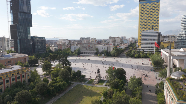 Aerial view of Skanderbeg Square featuring the statue of Skanderbeg historic buildings modern skyscrapers and people walking across the plaza in Tirane Qarku i Tiranes Albania.