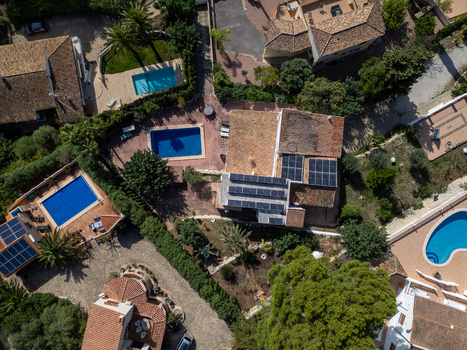 Aerial view of a residential villa in Moraira featuring a swimming pool solar panels on the roof and surrounding Mediterranean gardens Moraira Valencian Community Spain.