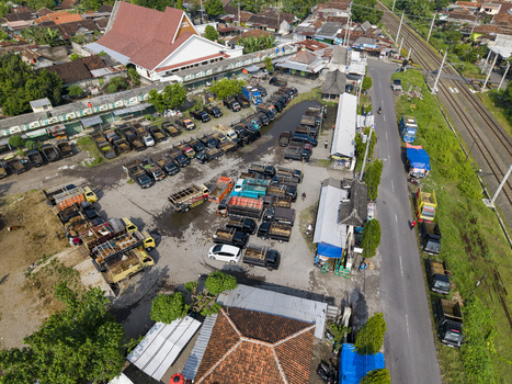 Aerial view of Animal Market Prambanan with trucks parked in the lot near a large white building and railway tracks in Kecamatan Prambanan Jawa Tengah Indonesia. Aerial view of Animal Market Prambanan with trucks parked in the lot near a large white building and railway tracks in Kecamatan Prambanan Jawa Tengah Indonesia.