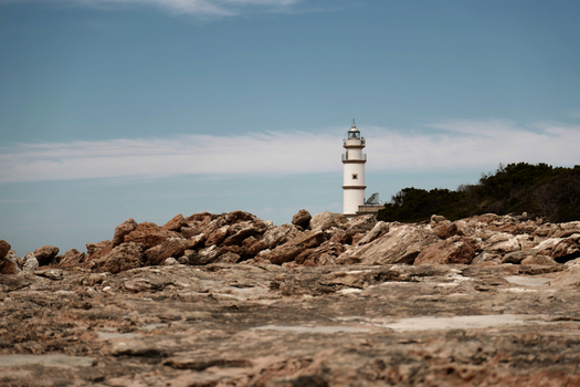 View of the lighthouse standing on the rocky coastline of Mallorca Balearic Islands Spain.