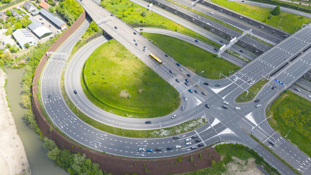 Aerial view of the Stadsbaan Leidsche Rijn highway interchange featuring a large circular ramp and moving vehicles surrounded by green fields in Utrecht Utrecht Netherlands. Aerial view of the Stadsbaan Leidsche Rijn highway interchange featuring a large circular ramp and moving vehicles surrounded by green fields in Utrecht Utrecht Netherlands.