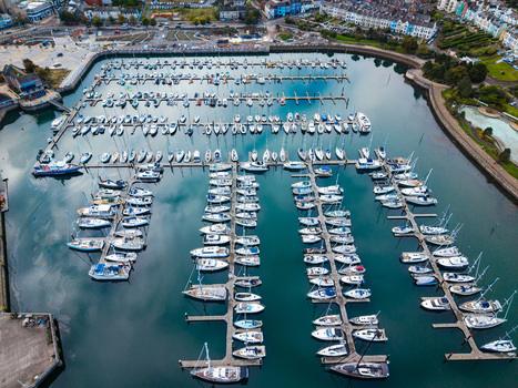 Aerial view of Bangor Harbour and Town with numerous sailboats docked in the marina surrounded by urban buildings and coastal infrastructure in Bangor Northern Ireland United Kingdom.