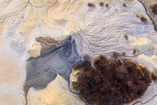 Aerial view of the Mud Volcanoes of Paclele Mari showcasing unique grey mud formations cracked earth patterns and sparse vegetation in Paclele Buzau County Romania.