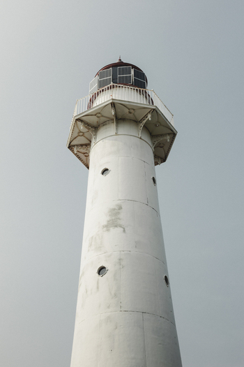 View of Saxby Lighthouse a white cylindrical tower with a red lantern room and solar panels set against a clear grey sky in Saxby Laane maakond Estonia.