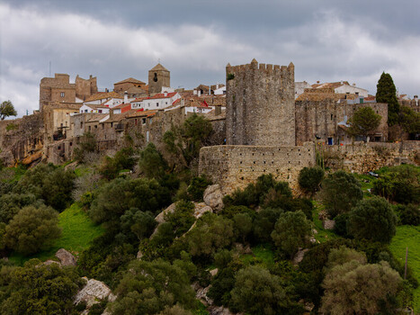 Aerial view of the ancient stone castle and white washed buildings perched high on a hill contrasting with the vibrant green vegetation Castellar de la Frontera Andalusia Spain. Aerial view of the ancient stone castle and white washed buildings perched high on a hill contrasting with the vibrant green vegetation Castellar de la Frontera Andalusia Spain.