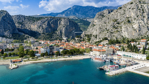 Aerial view of the coastal town nestled between dramatic limestone cliffs and the turquoise Adriatic Sea with boats moored in the harbor Omis Split Dalmatia County Croatia. Aerial view of the coastal town nestled between dramatic limestone cliffs and the turquoise Adriatic Sea with boats moored in the harbor Omis Split Dalmatia County Croatia.