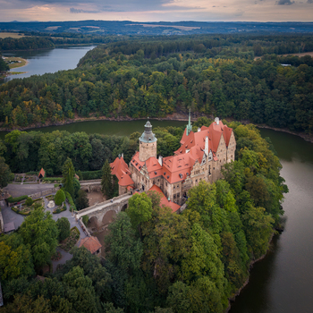 Aerial view of Czocha Castle with its distinctive red roofs and stone bridge surrounded by lush forest and the Kwisa river in Sucha Wojewodztwo dolnoslaskie Poland. Aerial view of Czocha Castle with its distinctive red roofs and stone bridge surrounded by lush forest and the Kwisa river in Sucha Wojewodztwo dolnoslaskie Poland.