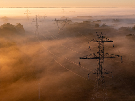 Aerial view of transmission lines and towers rising through thick morning fog at sunrise in a rural landscape Bridgman Michigan United States.