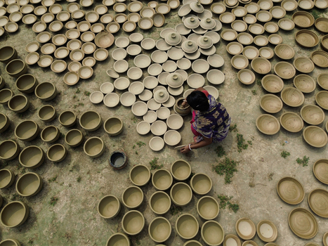 Joypurhat Bangladesh 28 September 2026 Aerial view of a woman crafting traditional clay pottery in an open field surrounded by numerous drying earthenware bowls. Joypurhat Bangladesh 28 September 2026 Aerial view of a woman crafting traditional clay pottery in an open field surrounded by numerous drying earthenware bowls.