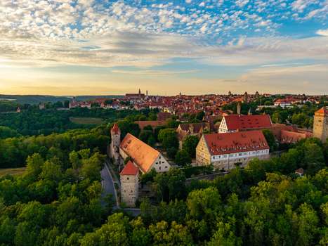 Aerial view of Rothenburg ob der Tauber with red tiled roofs and medieval fortifications under a golden sunset sky in Rothenburg ob der Tauber Bavaria Germany. Aerial view of Rothenburg ob der Tauber with red tiled roofs and medieval fortifications under a golden sunset sky in Rothenburg ob der Tauber Bavaria Germany.
