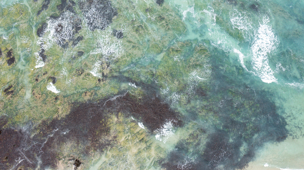 Aerial view of the turquoise water and waves crashing over the rocky shoreline at Constantine Bay in Padstow Cornwall United Kingdom. Aerial view of the turquoise water and waves crashing over the rocky shoreline at Constantine Bay in Padstow Cornwall United Kingdom.