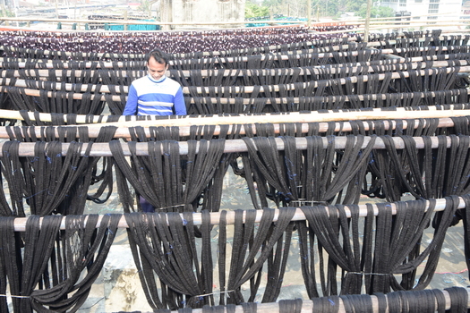 Kushtia Khulna Division Bangladesh 27 December 2019 View of a worker drying black dyed yarn on bamboo racks in a traditional textile workshop. Kushtia Khulna Division Bangladesh 27 December 2019 View of a worker drying black dyed yarn on bamboo racks in a traditional textile workshop.