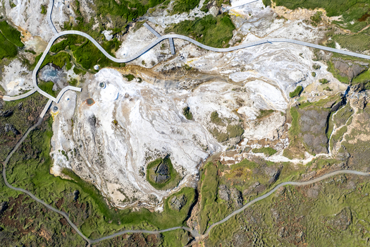 Aerial view of Hveravellir geothermal area featuring white mineral deposits steaming vents and wooden boardwalks winding through the landscape in Hunabyggd Iceland. Aerial view of Hveravellir geothermal area featuring white mineral deposits steaming vents and wooden boardwalks winding through the landscape in Hunabyggd Iceland.