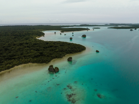 Aerial view of the vibrant turquoise waters meeting the lush green coastline speckled with rocky outcrops Pine Island L Île des Pins New Caledonia. Aerial view of the vibrant turquoise waters meeting the lush green coastline speckled with rocky outcrops Pine Island L Île des Pins New Caledonia.