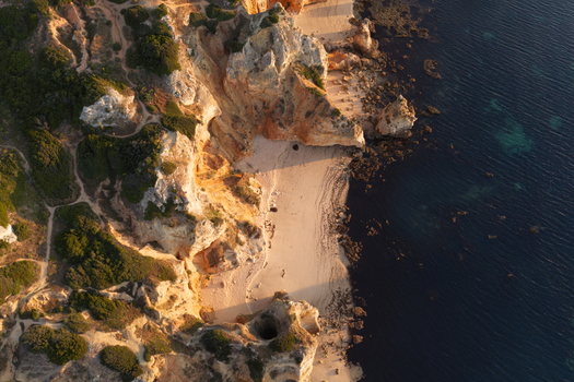 Aerial view of the dramatic golden sandstone cliffs and secluded sandy beach at Ponta da Piedade in Lagos Faro District Portugal.