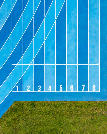 Aerial view of a blue running track with lanes numbered one through eight and adjacent green grass in Plock Masovian Voivodeship Poland.